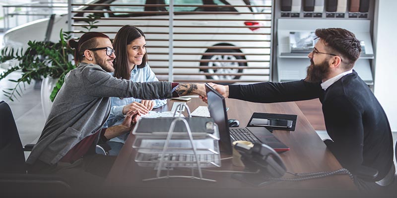 Couple sitting in an office shaking hands with sales person.