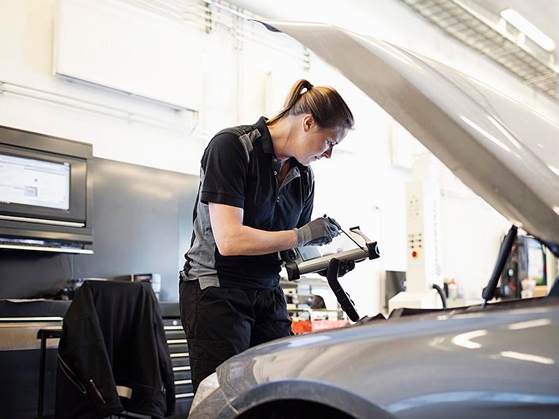 Service technician going looking at an engine bay taking notes.